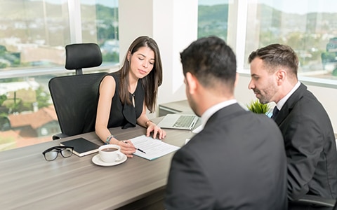Three people having a meeting in an office and going over a contract