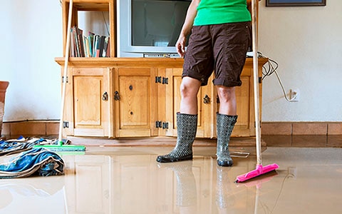 person with rain boots on cleaning up water 