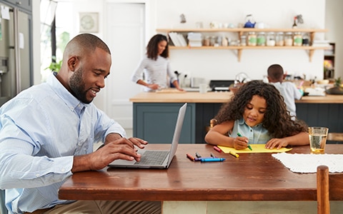 man working at table with daughter, 6 home organizing projects to keep your children busy while you're working from home