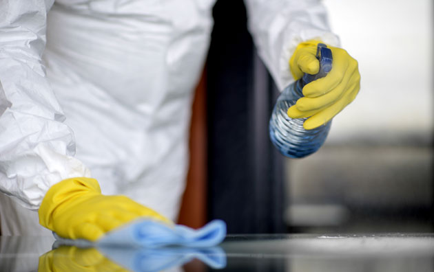 a person in body covering and gloves cleaning a surface