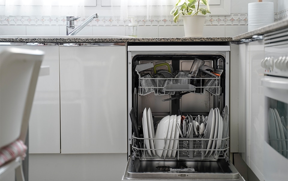 An open dishwasher full of dishes in a modern kitchen.