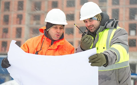 Two workers talking on walkie outside in the snow