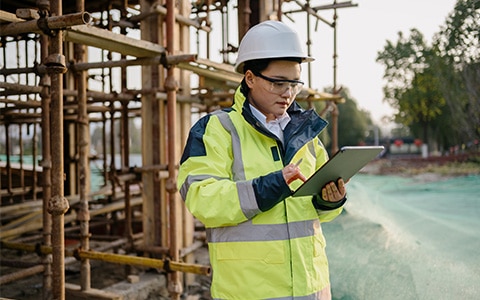 Female construction worker at jobsite looking at tablet