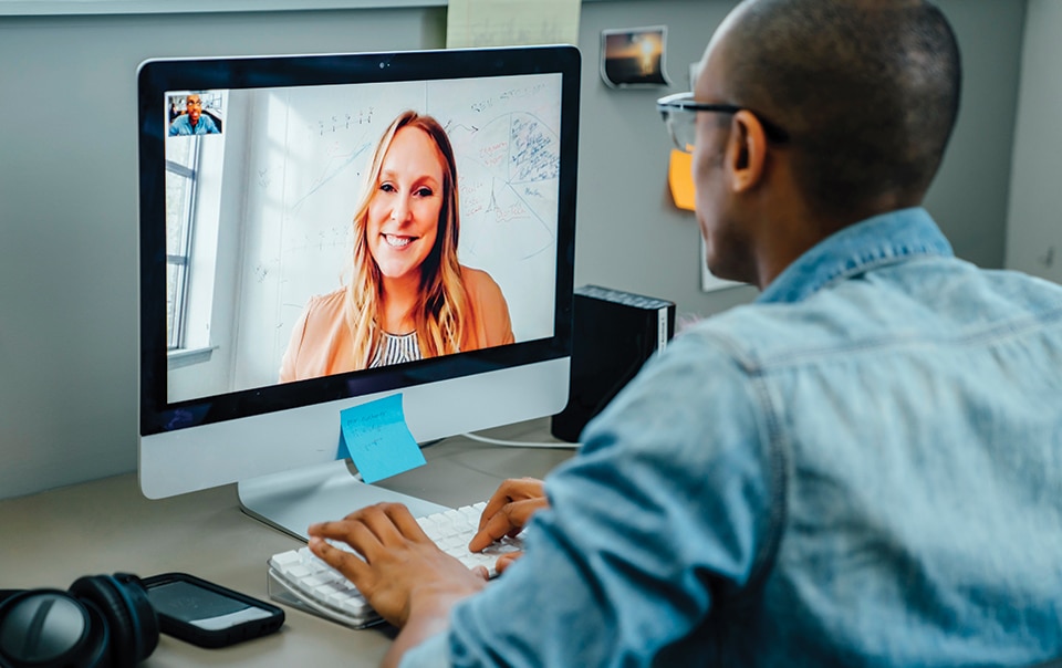 A man virtually conferencing with a woman using a desktop computer