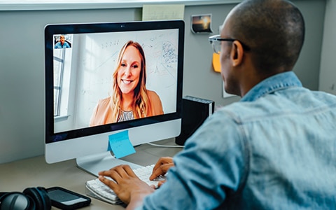 a man on his desktop computer video chatting with a woman