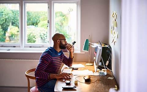 man at desk in front of  a window at home while he works, Cybersecutiy for Employees Working From Home