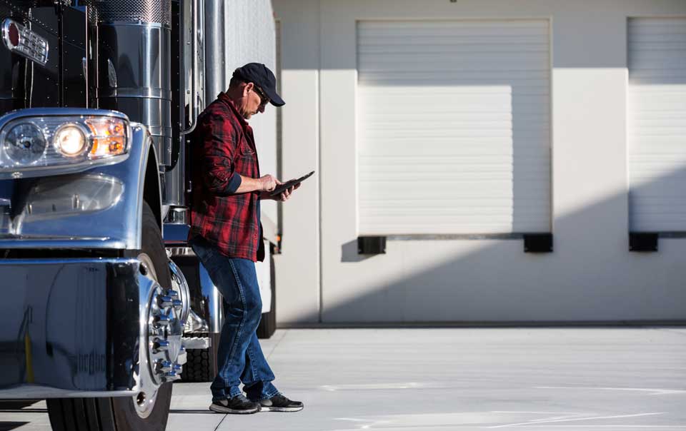 Truck driver looking at tablet next to truck