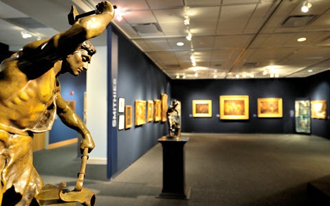 A brass metal statue of a man at work in a museum.