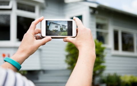 woman takes picture of house with smart phone