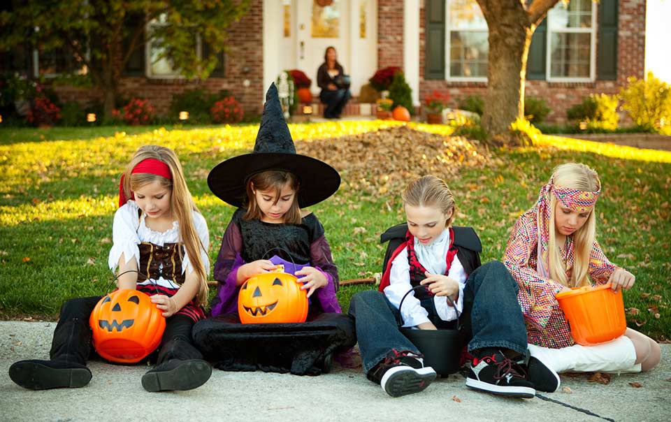 Kids in Halloween costumes sitting on the sidewalk