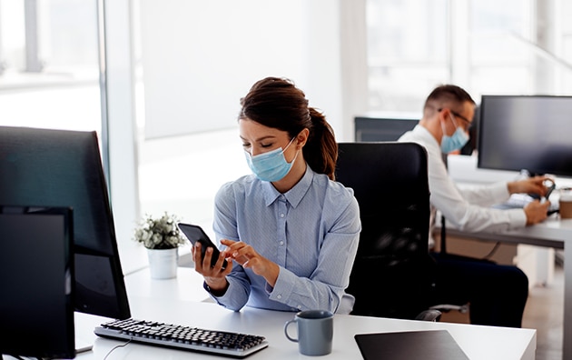 two people working in the office while wearing masks. How to Keep Your Employees Save in the Workplace During COVID-19