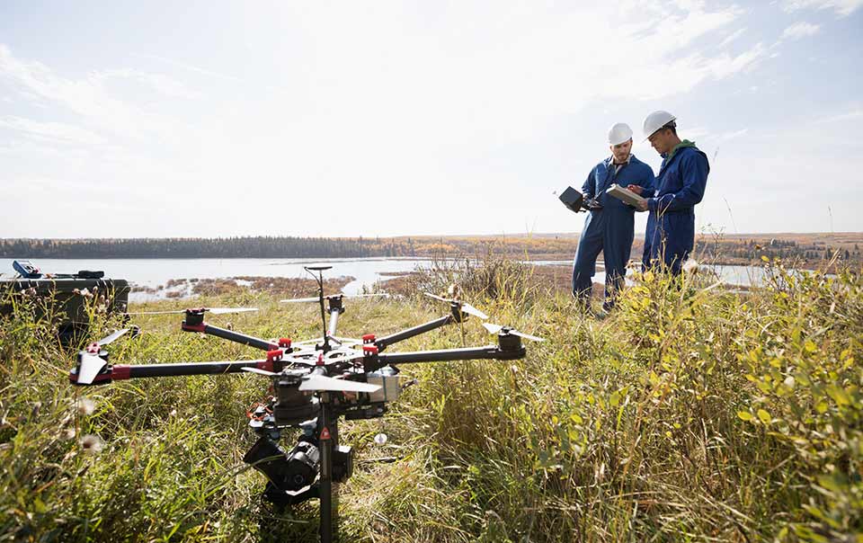 Two business workers operating drone in field