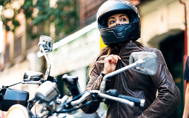 motorcyclist preparing for a ride, wearing a helmet and leather jacket