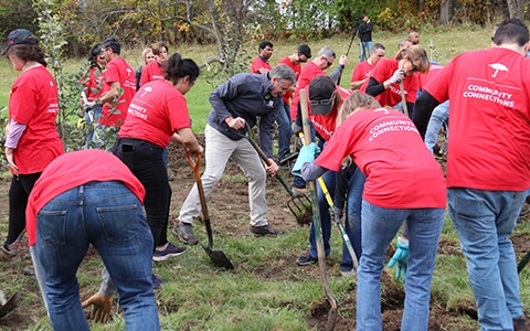 Travelers employees with shovels to plant trees, Go Paperless for a Purpose