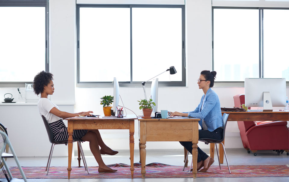 Two young professionals sitting at desks in open office