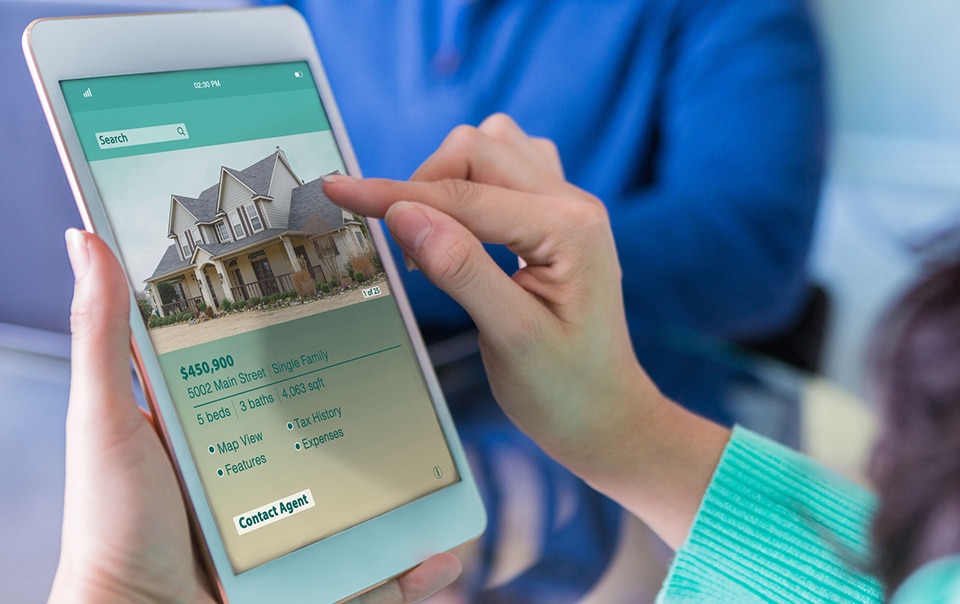 person viewing home listings online, pros and cons of buying a house now