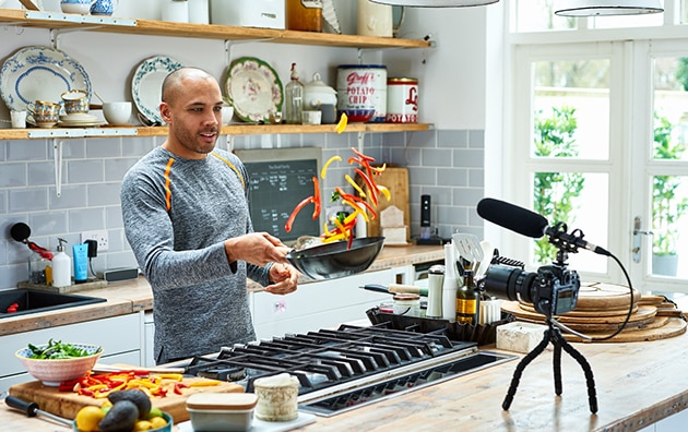man cooking at home in front of a camera for online viewing