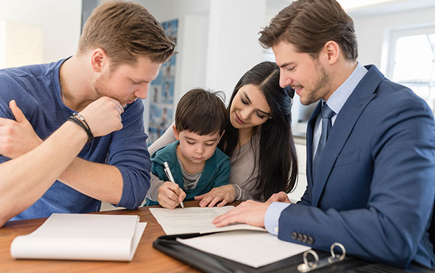 family signing insurance papers after buying new home