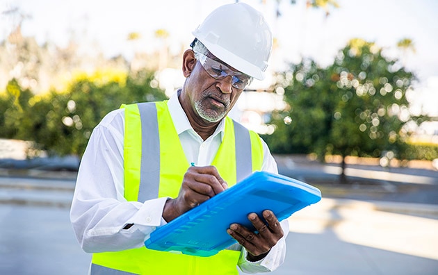 Construction worker holding a clipboard looking over paperwork