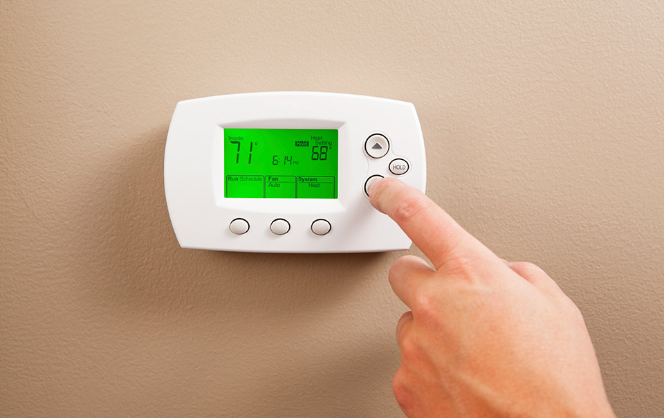 Person adjusting thermostat as part of home winterization